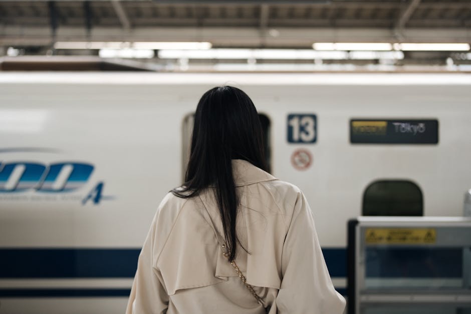 東京の駅で高速新幹線を待ち受ける女性。旅と期待を象徴する。