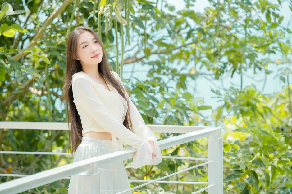 若い女性が豊かな緑に囲まれたバルコニーで晴れた日を楽しんでいます。
