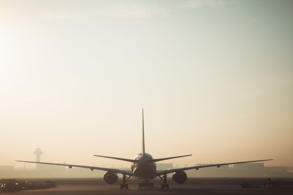 霧のかかった朝のシーン。滑走路にいる飛行機と、ぼんやりした空の背景が空の旅の雰囲気を表現します。