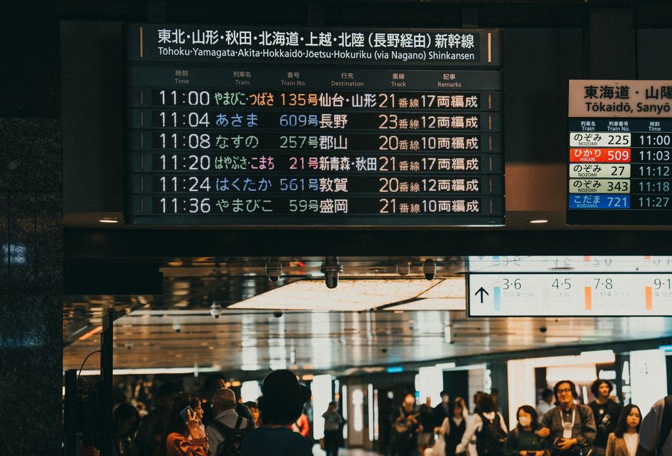 時刻表を表示するデジタル発車案内板が設置された、日本の混雑した駅。