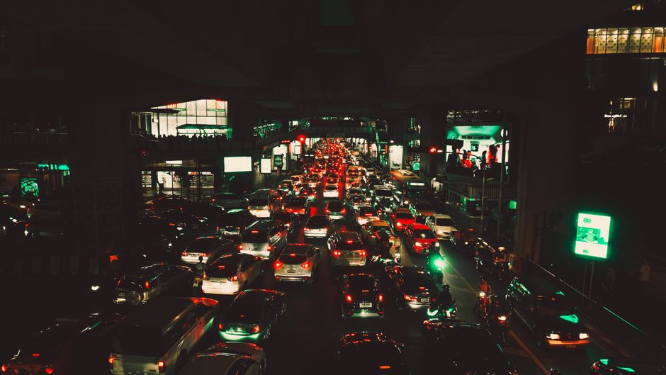 明るいライトと周辺の照明された建物がある都市の道路での重交通のダイナミックな夜景シーン。