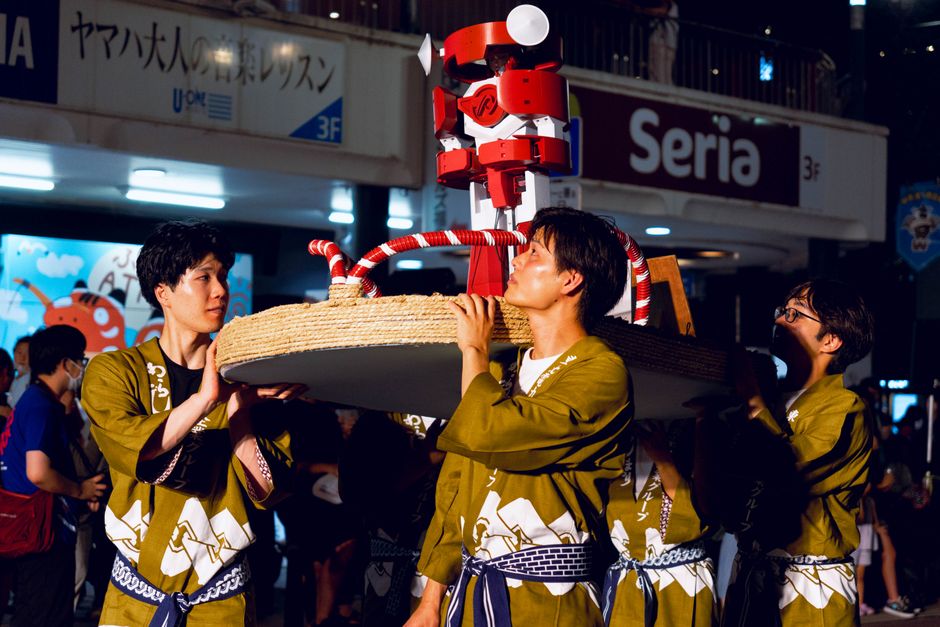 日本の伝統的な祭りの夜に山車を担ぐ参加者たち。