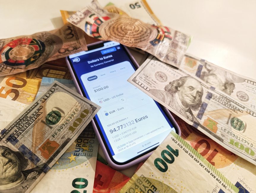 ドル紙幣とユーロ紙幣に囲まれた通貨換算機が表示されたスマートフォンで、為替レートが強調表示されています。