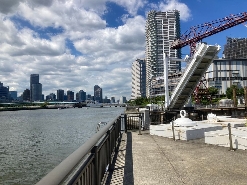 目立つ跳ね橋と澄み切った青空を背景にした、隅田川沿いの東京の近代的なスカイラインの美しい景色。