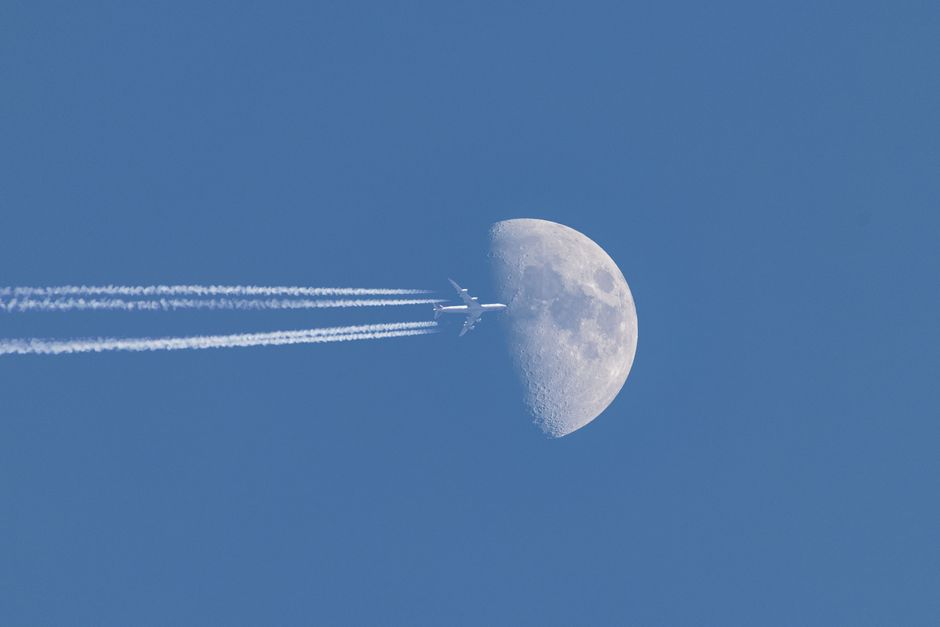 カナダのトロントの上空で明るい昼間の月を横切る飛行機の素晴らしい眺め。