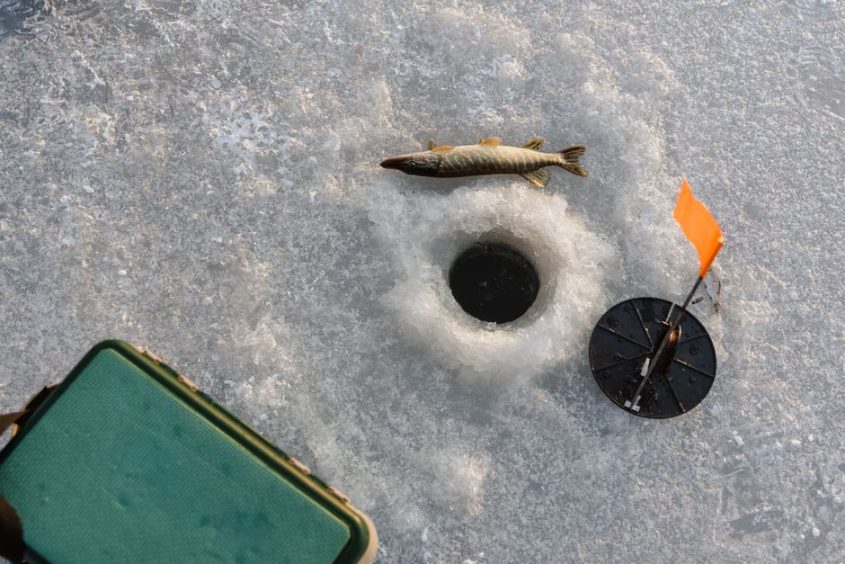 氷上釣りのシーン、捕まえた魚、氷穴、そして凍った湖面上の設備。