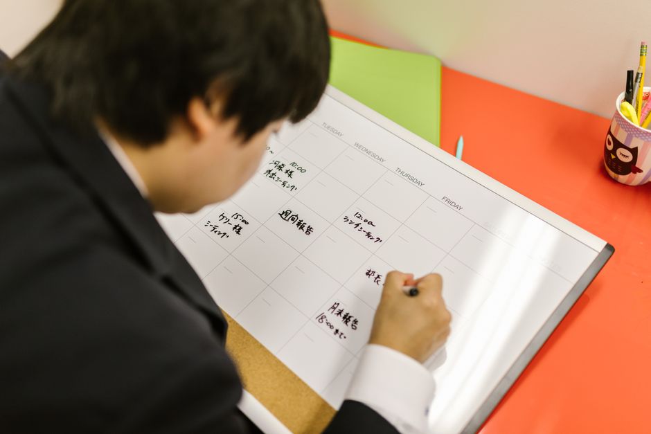 ビジネスパーソンがデスクのプランナーに書き込み、週のスケジュールを専門的に整理しています。